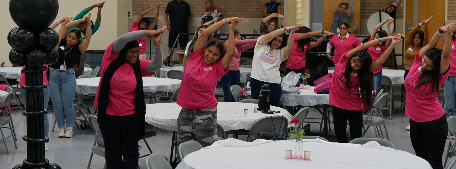 Female students in pink shirts do stretches as part of Black & Brown Girls Wellness Day