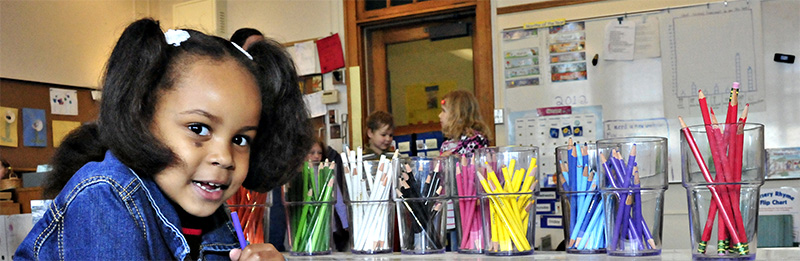 Preschooler draws with brightly colored pencils
