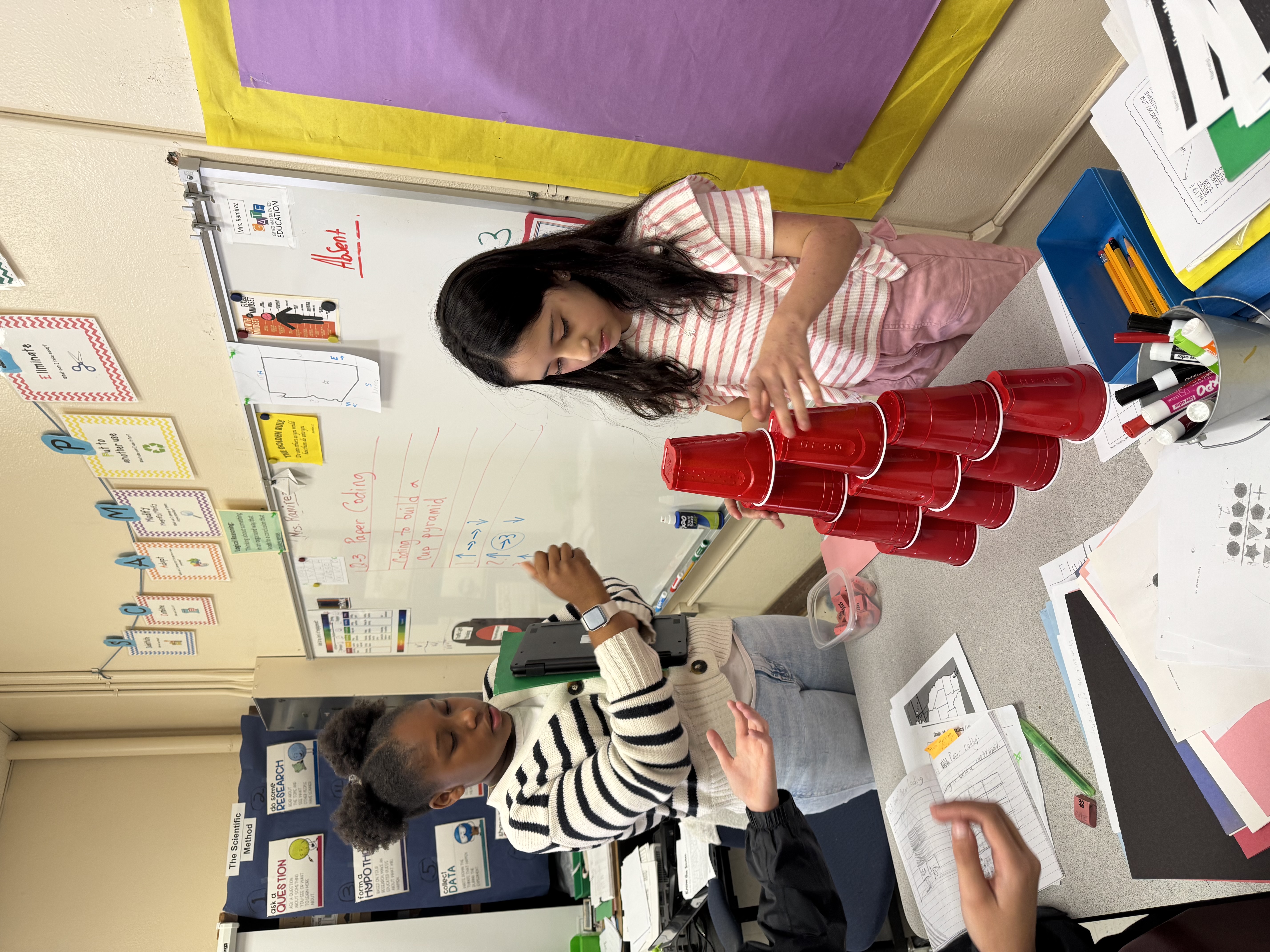 Student participating in a challenge involving stacking cups 4 then 3, then 2, then 1.