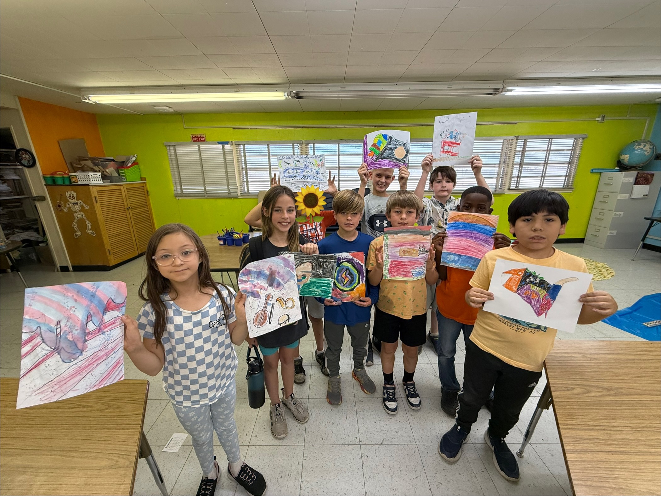 Students holding up their watercolor paintings for all to see.