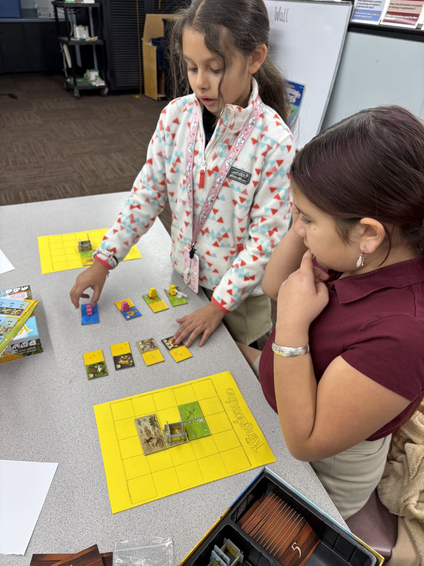 Elementary school student or students shown playing a board game called Kingdominoes.