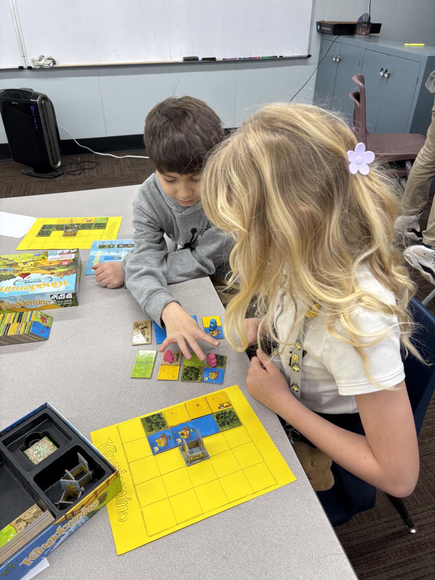 Elementary school student or students shown playing a board game called Kingdominoes.