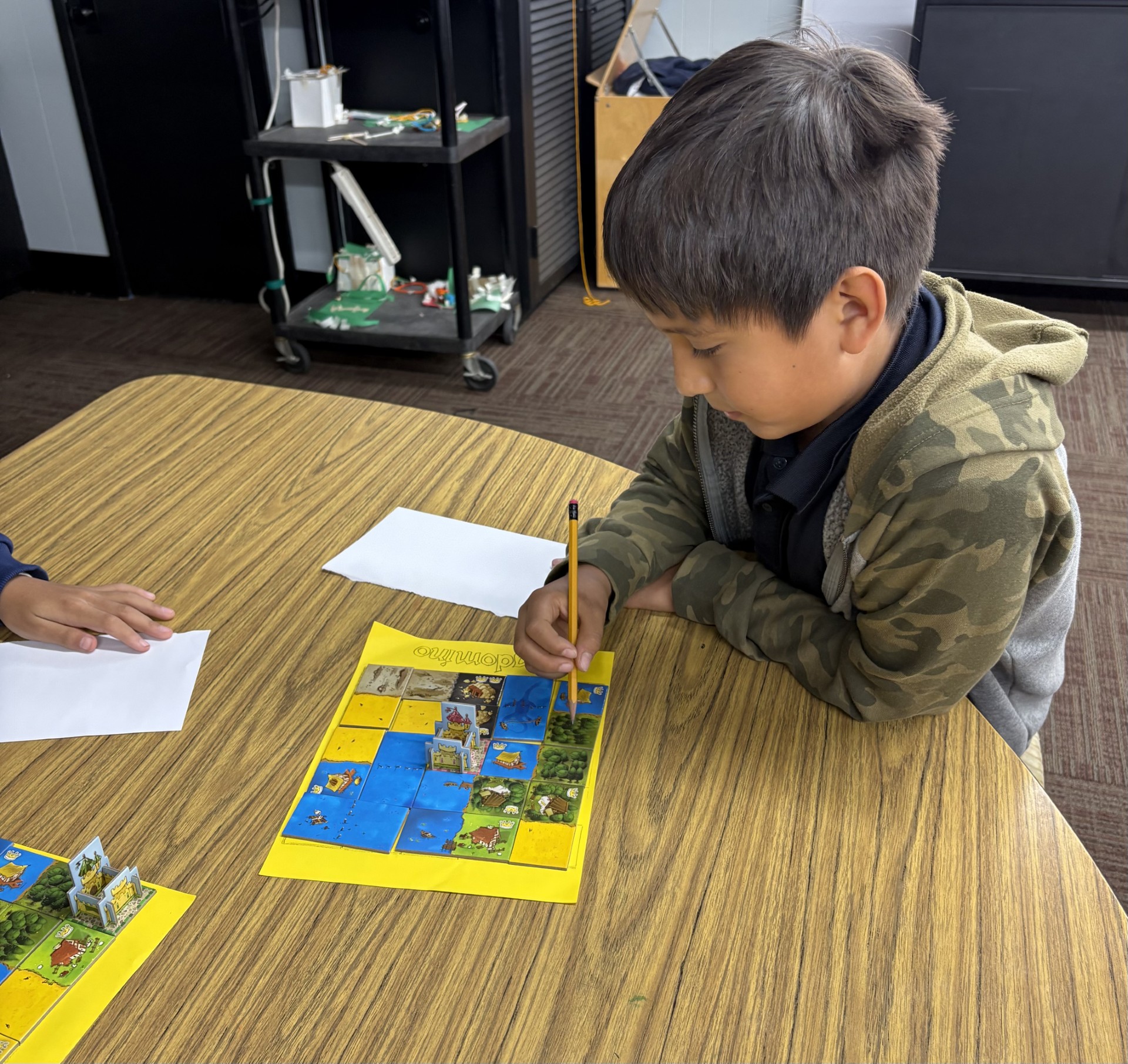 Elementary school student or students shown playing a board game called Kingdominoes.