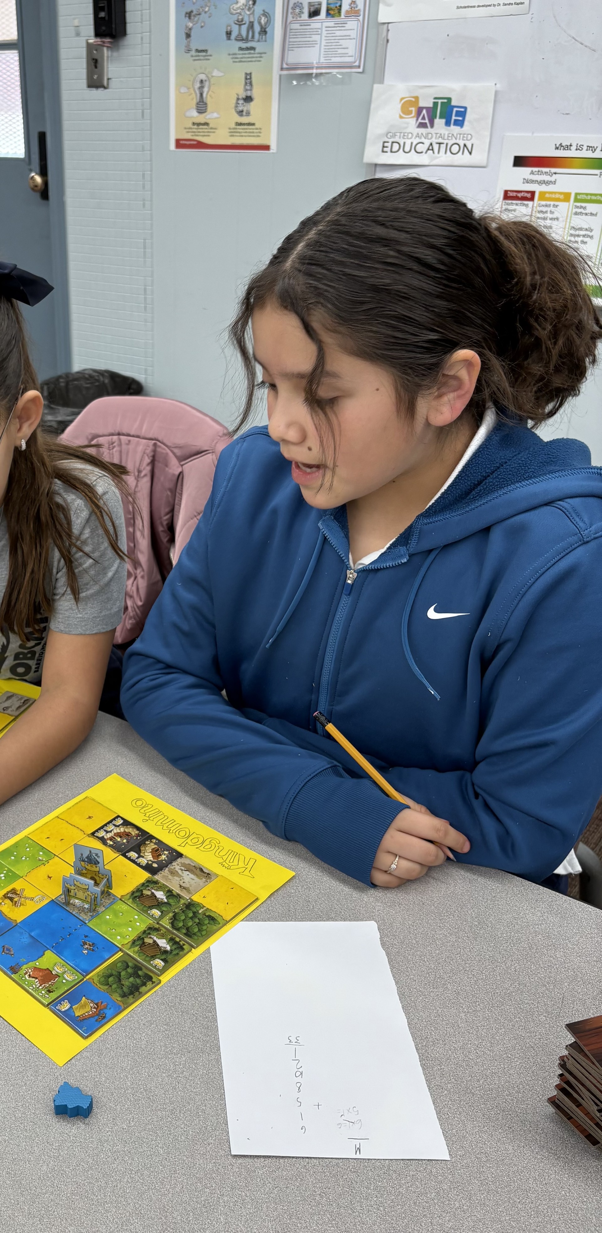 Elementary school student or students shown playing a board game called Kingdominoes.