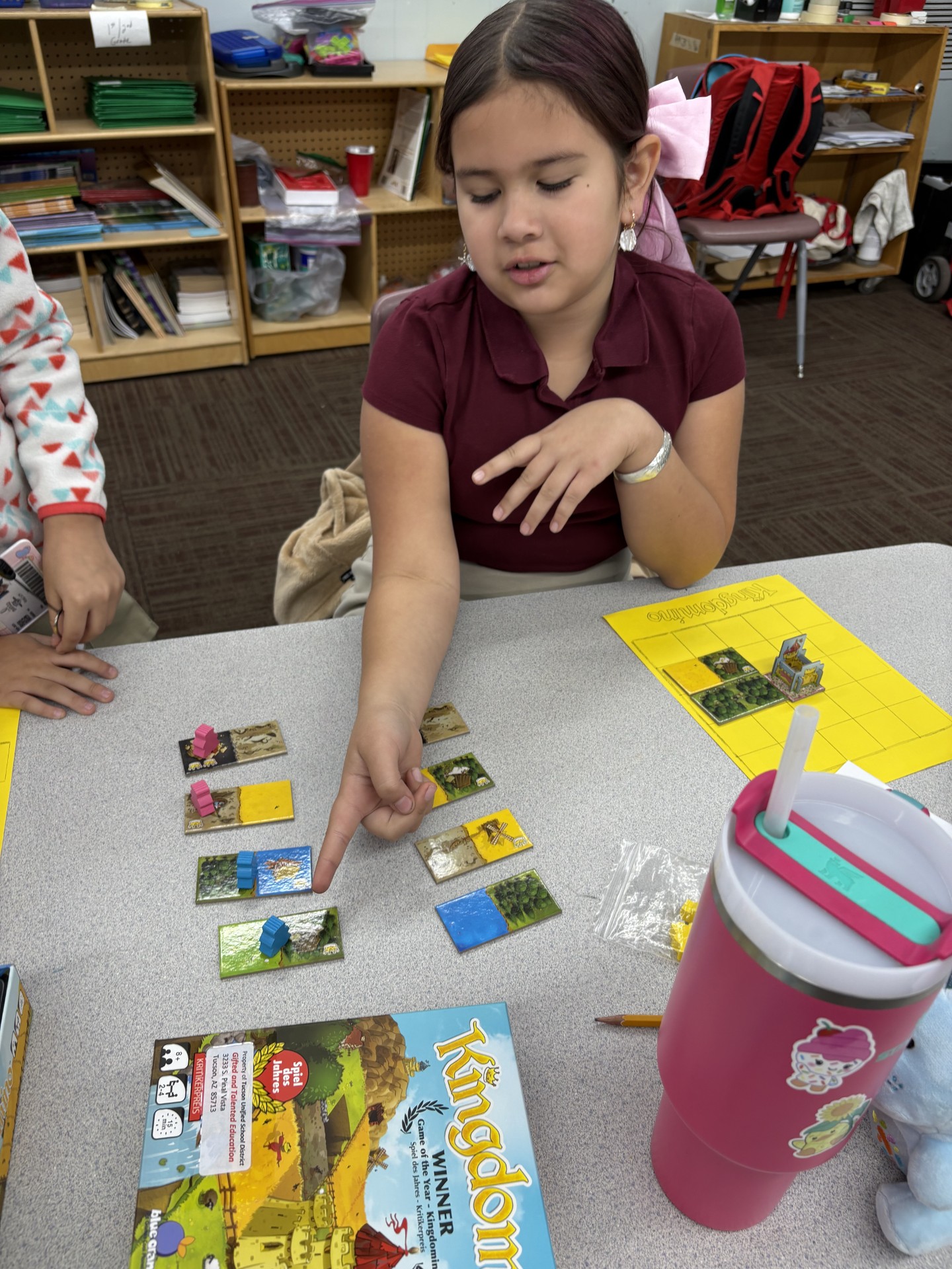 Elementary school student or students shown playing a board game called Kingdominoes.