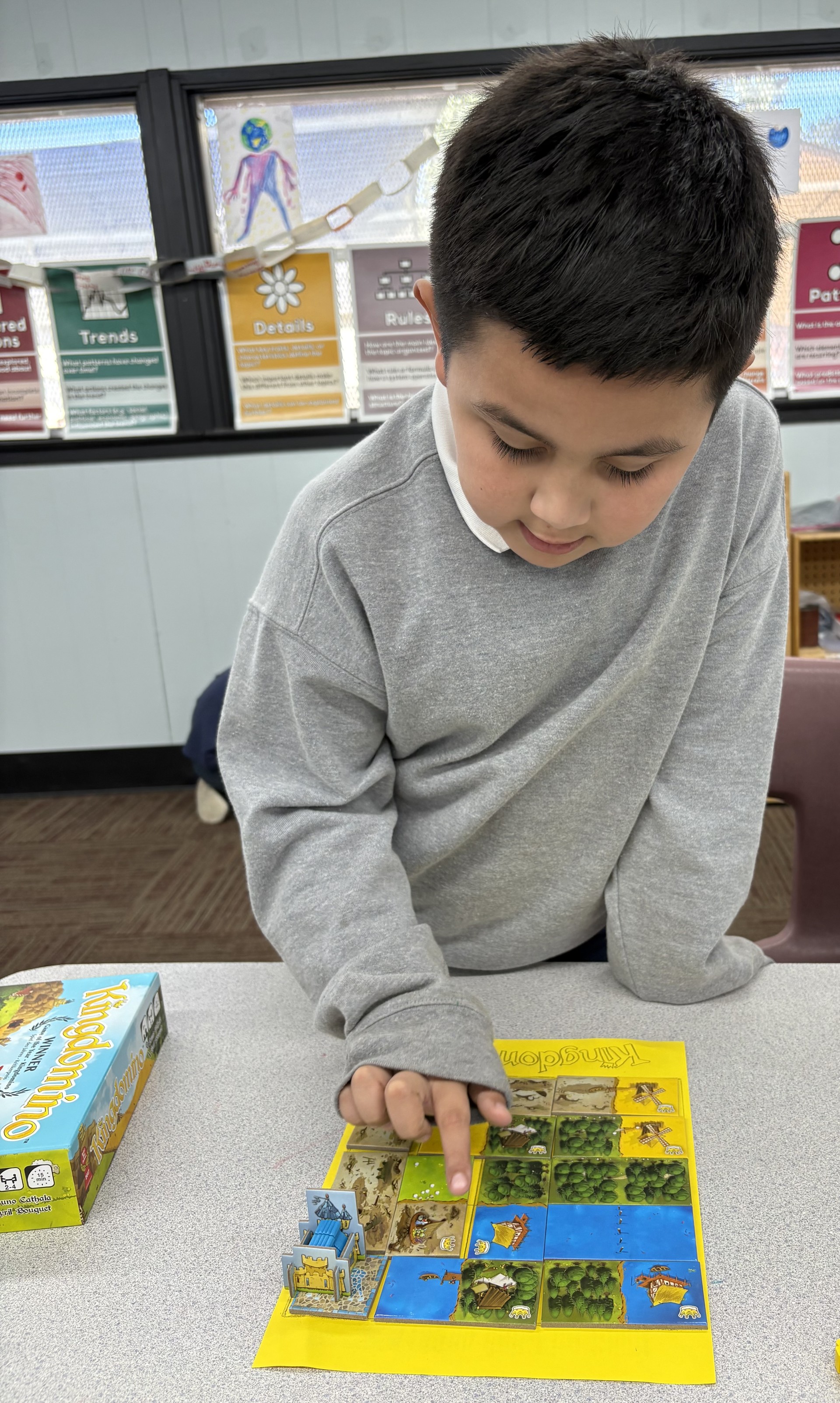 Elementary school student or students shown playing a board game called Kingdominoes.