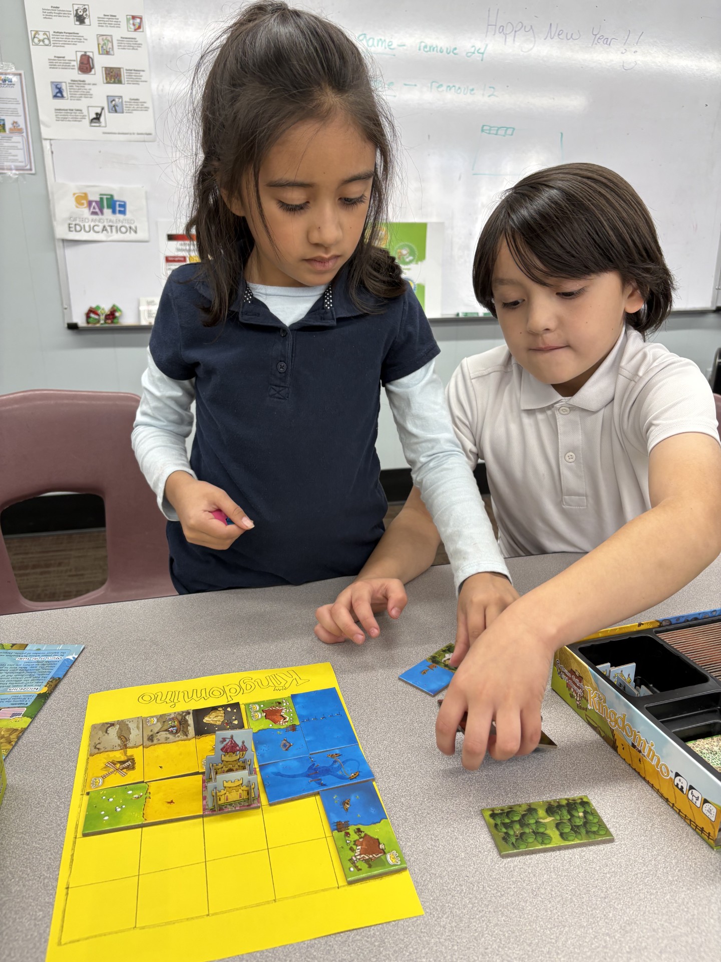 Elementary school student or students shown playing a board game called Kingdominoes.
