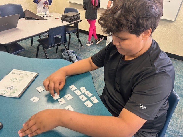 This picture shows a student participating in a letter logic-based activity as part of our Olympics of the Mind unit, engaging with one of Gardner’s multiple intelligences.
