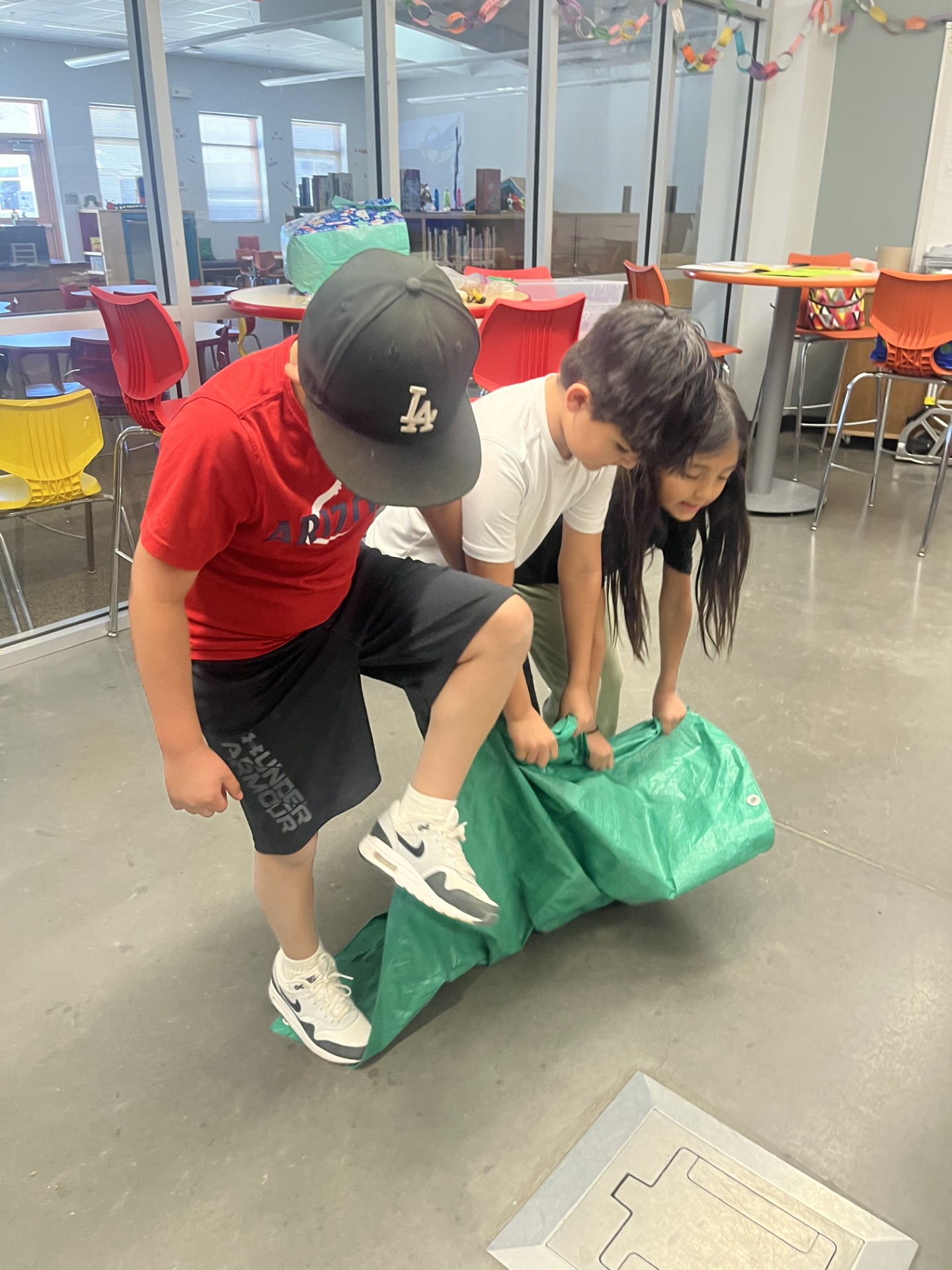 Students participating in an Olympics of the mind kinesthetic challenge trying to flip a tarp while standing on it..