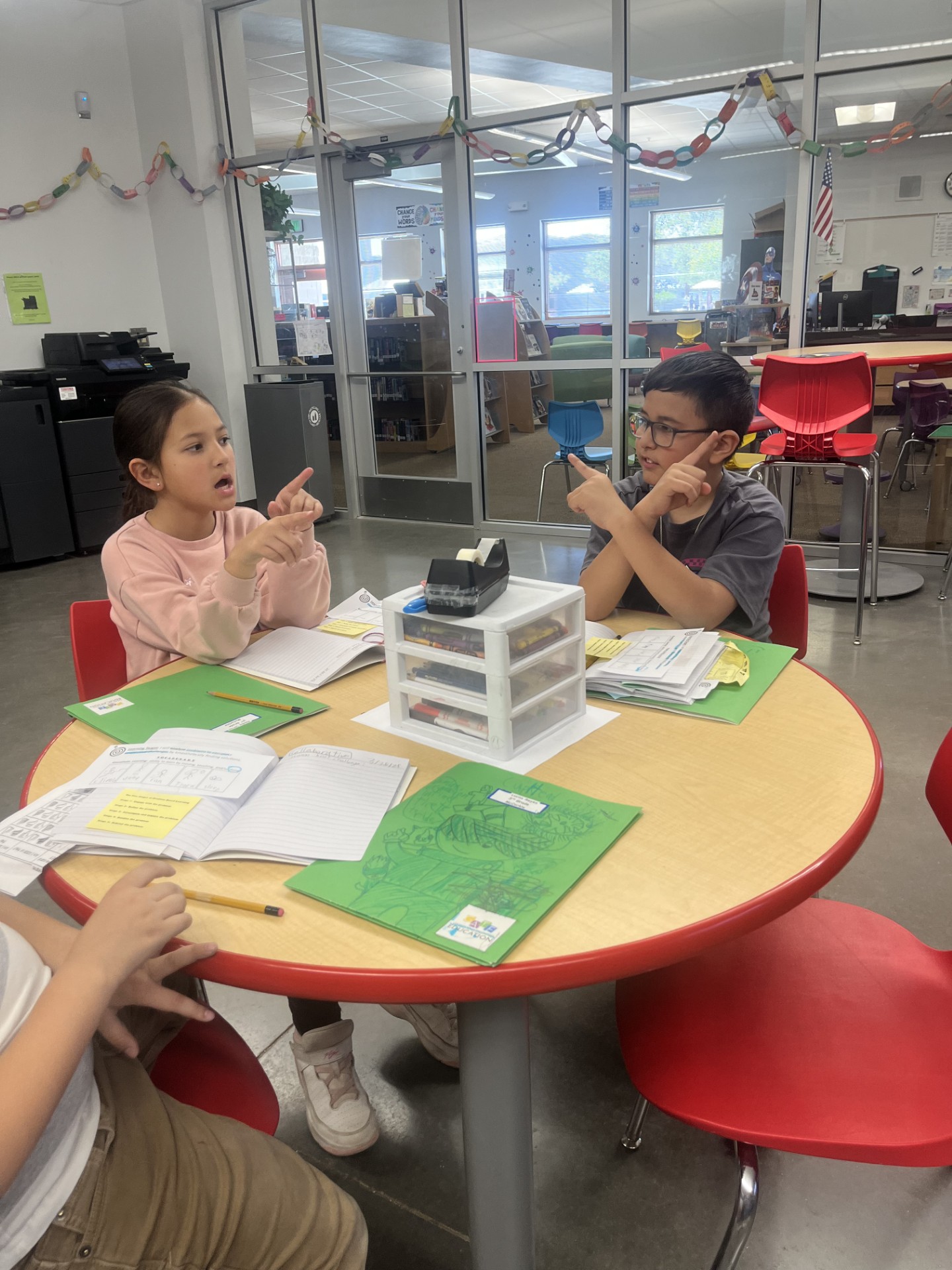 Students having a discussion during a class lesson while sitting around a table.