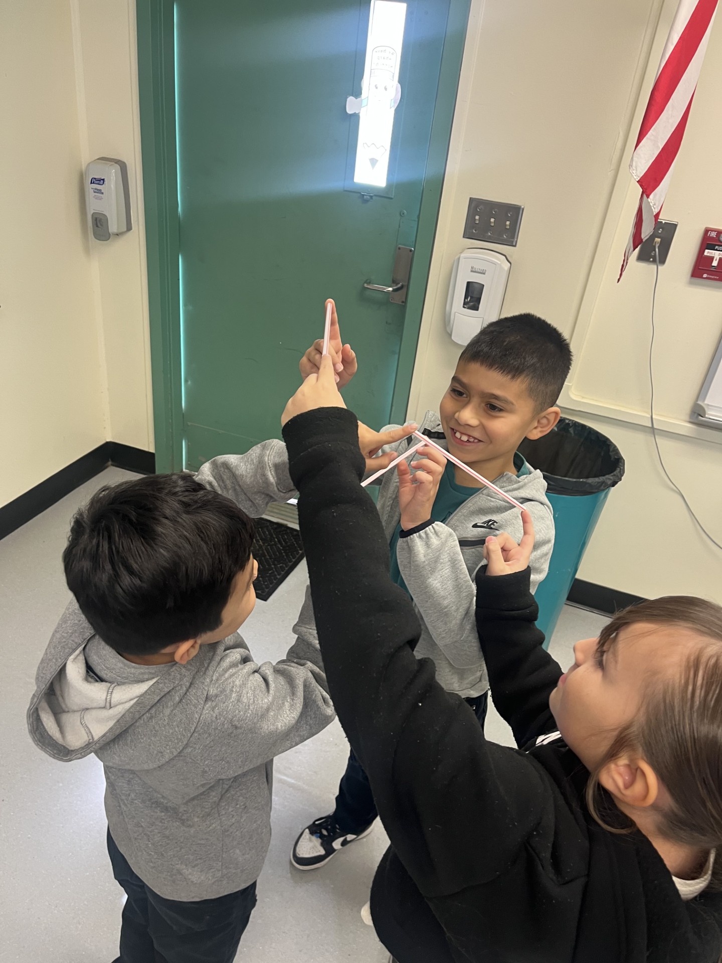 Students participating in a bodily kinesthetic challenge holding straws with one another while standing in a circle.
