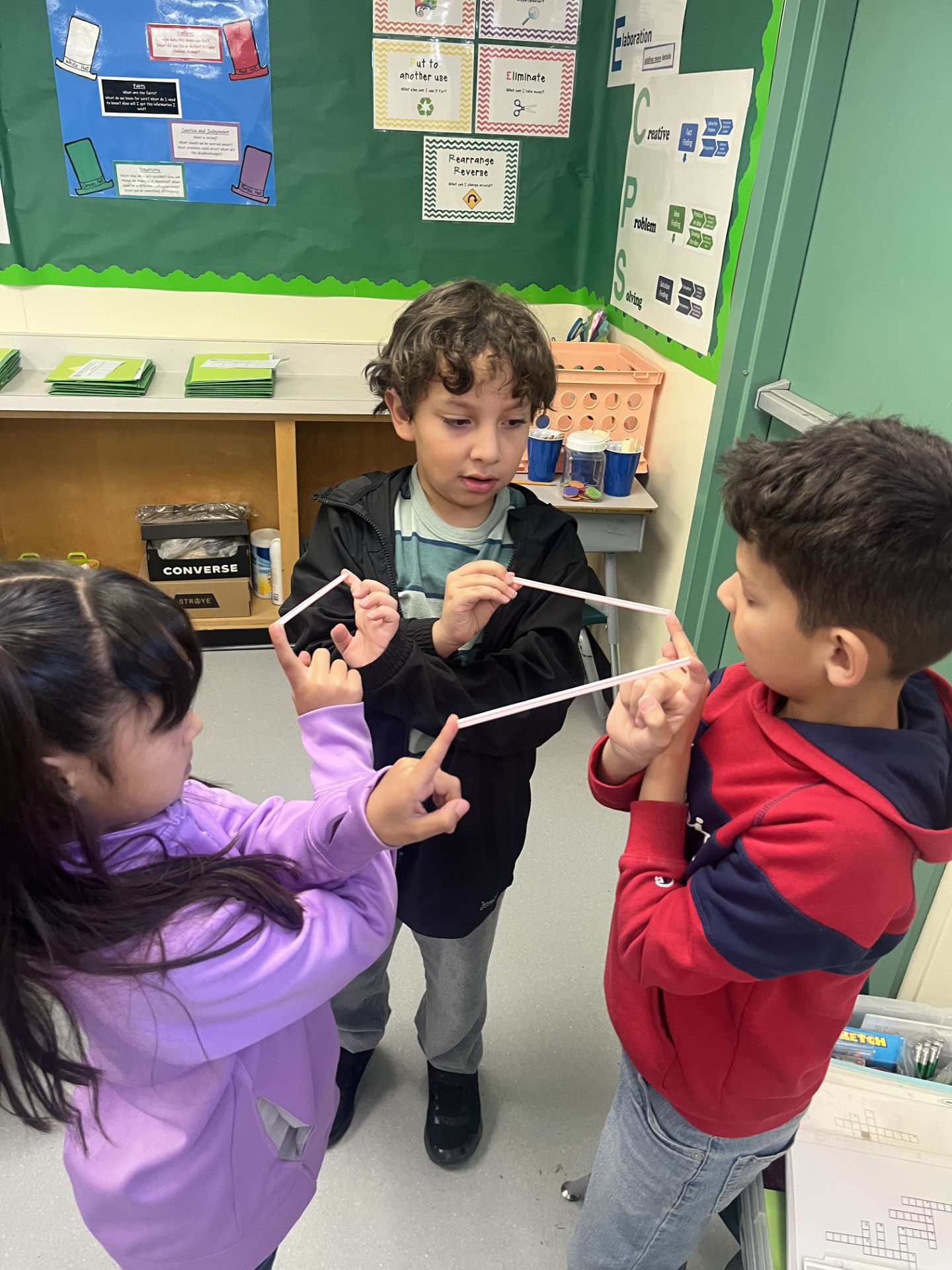 Students participating in a bodily kinesthetic challenge holding straws with one another while standing in a circle.