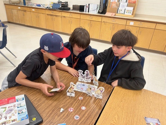 This picture shows students participating in a logic-based game, Dog Crimes, as part of our Olympics of the Mind unit, engaging with one of Gardner’s multiple intelligences.