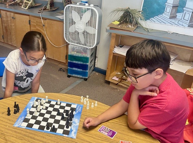 This picture shows students participating in a logic-based chess game as part of our Olympics of the Mind unit, engaging with one of Gardner’s multiple intelligences.