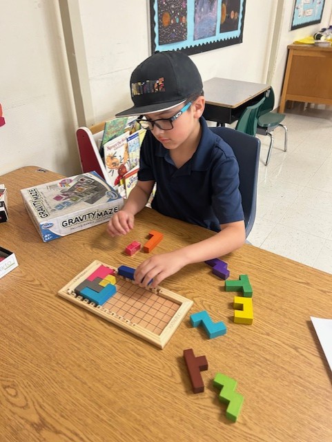 This picture shows a student (or students) participating in a logic-based activity, pentominoes, as part of our Olympics of the Mind unit, engaging with one of Gardner’s multiple intelligences.