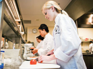 Students prepare food in a kitchen. 