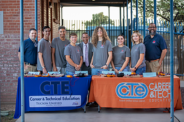 CTE Students and Staff standing behind table