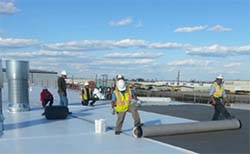 Construction crews work on the roof of a Tucson Unified building.