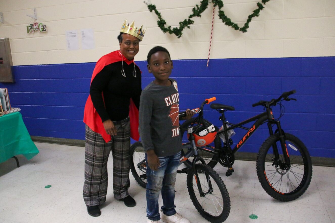 A boy smiles next to his brand new bicycle!