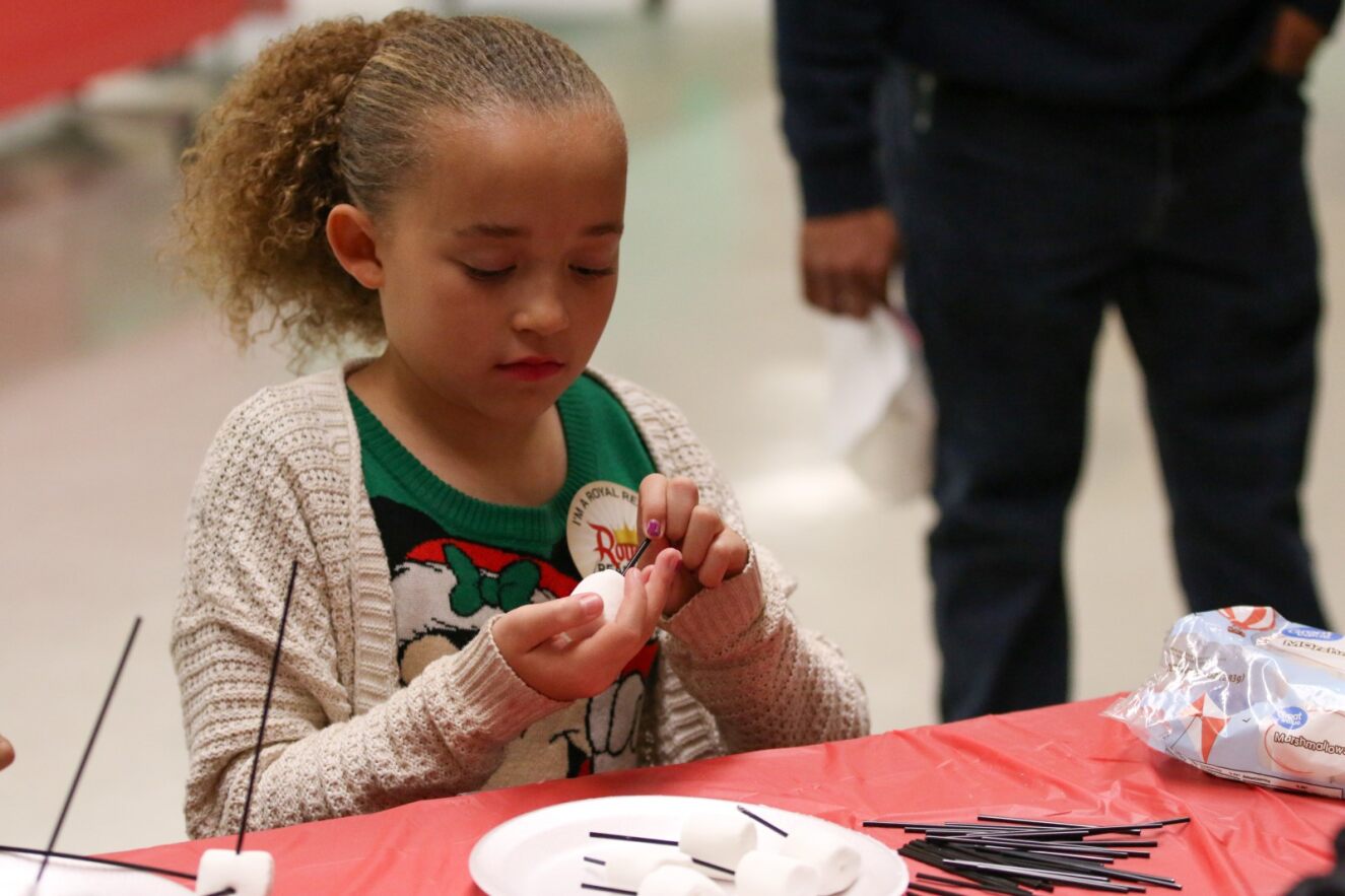 A young girl works on her marshmallow craft.