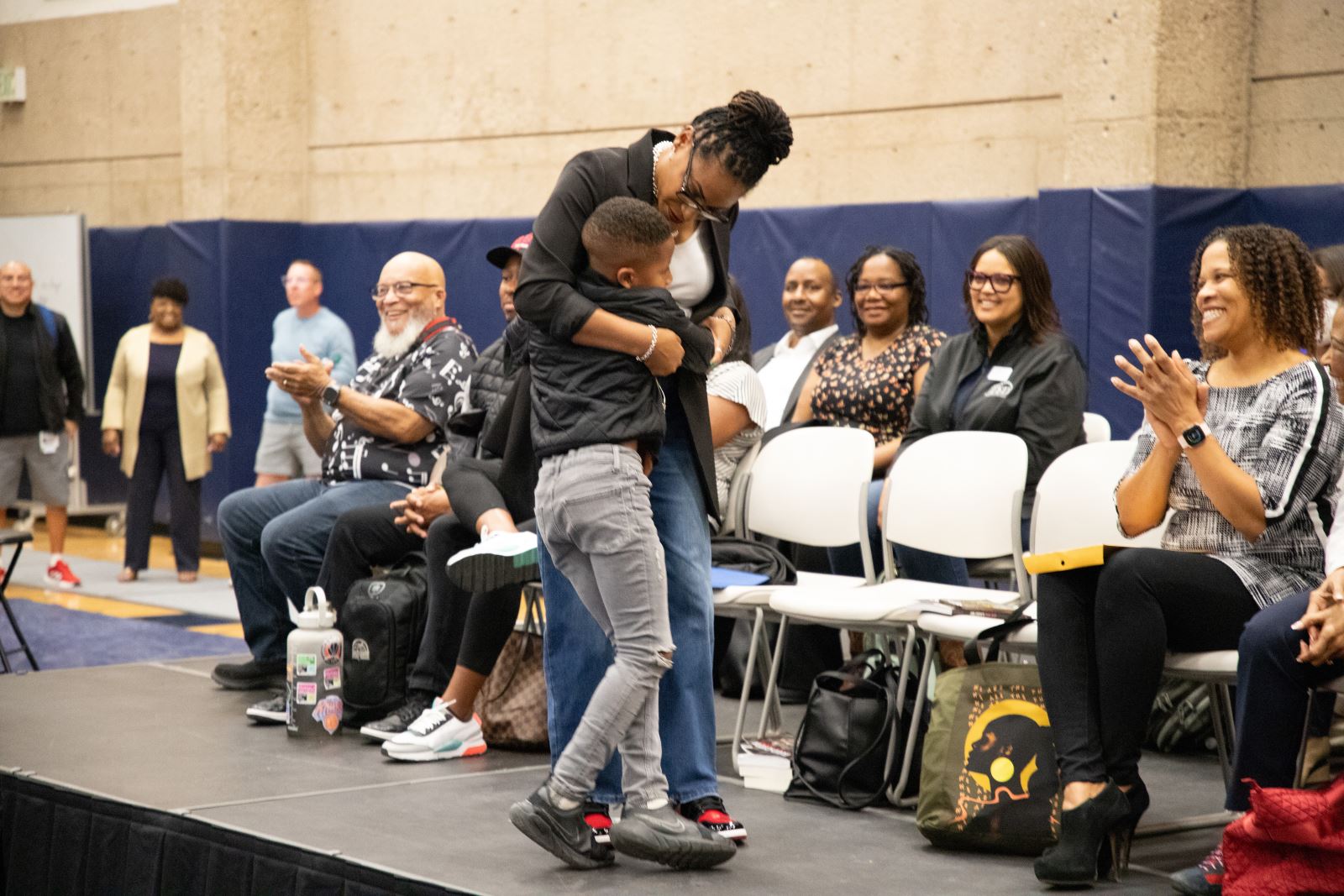 Dr. Tonya Strozier hugs her son while other speakers smile.