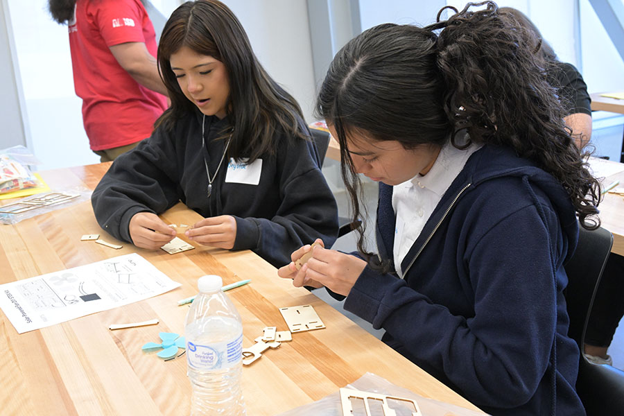 Two girls make something out of pieces of paper