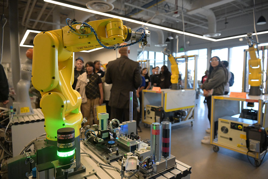 A yellow robotic arm in front of a group of students