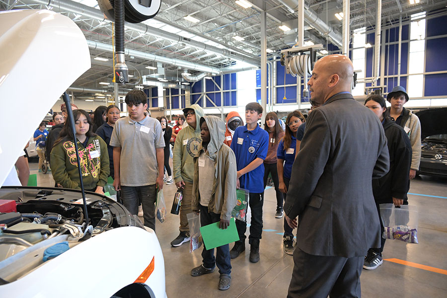 Students look at a car with its hood popped open