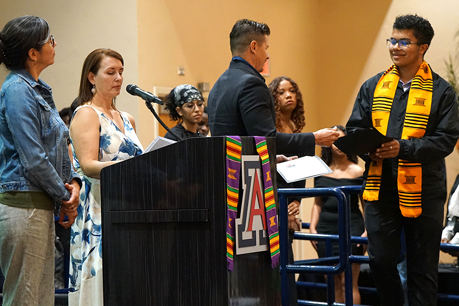 A teen boy shakes a man's hand as he receives an award certificate
