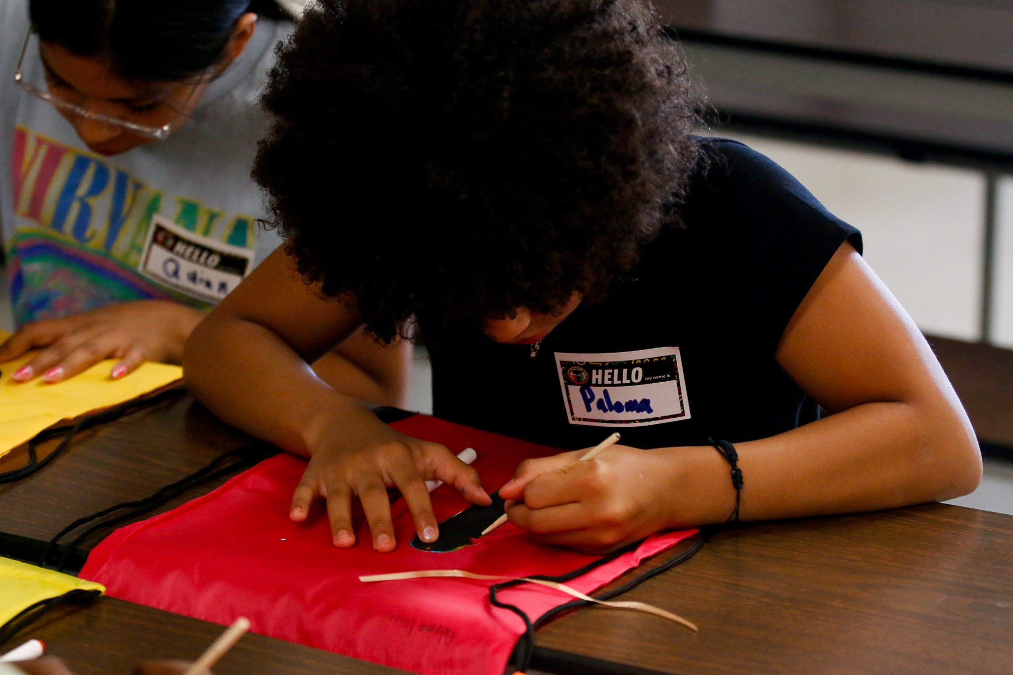 A girl draws on a piece of red paper