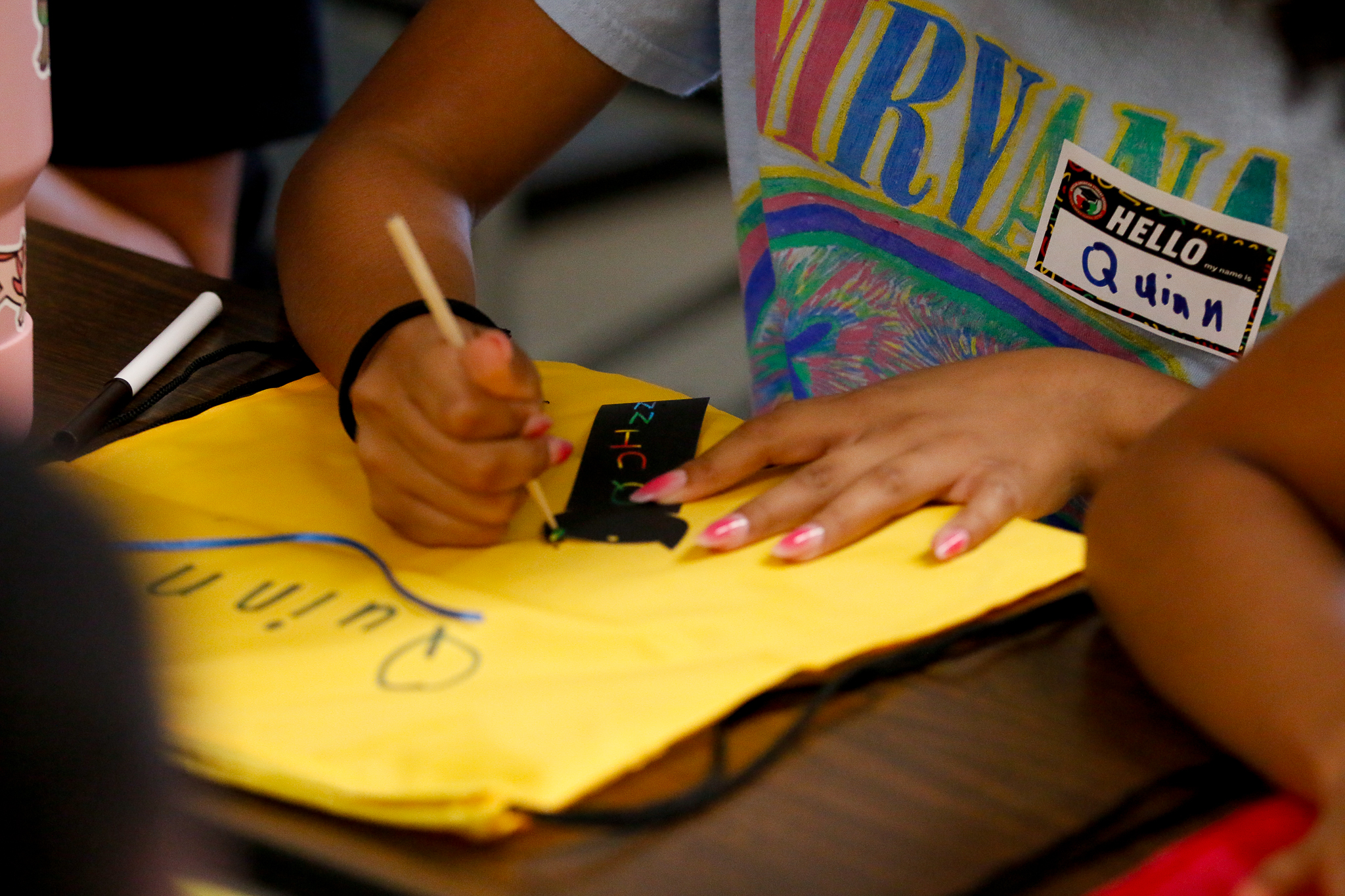 A girl draws on a yellow piece of paper