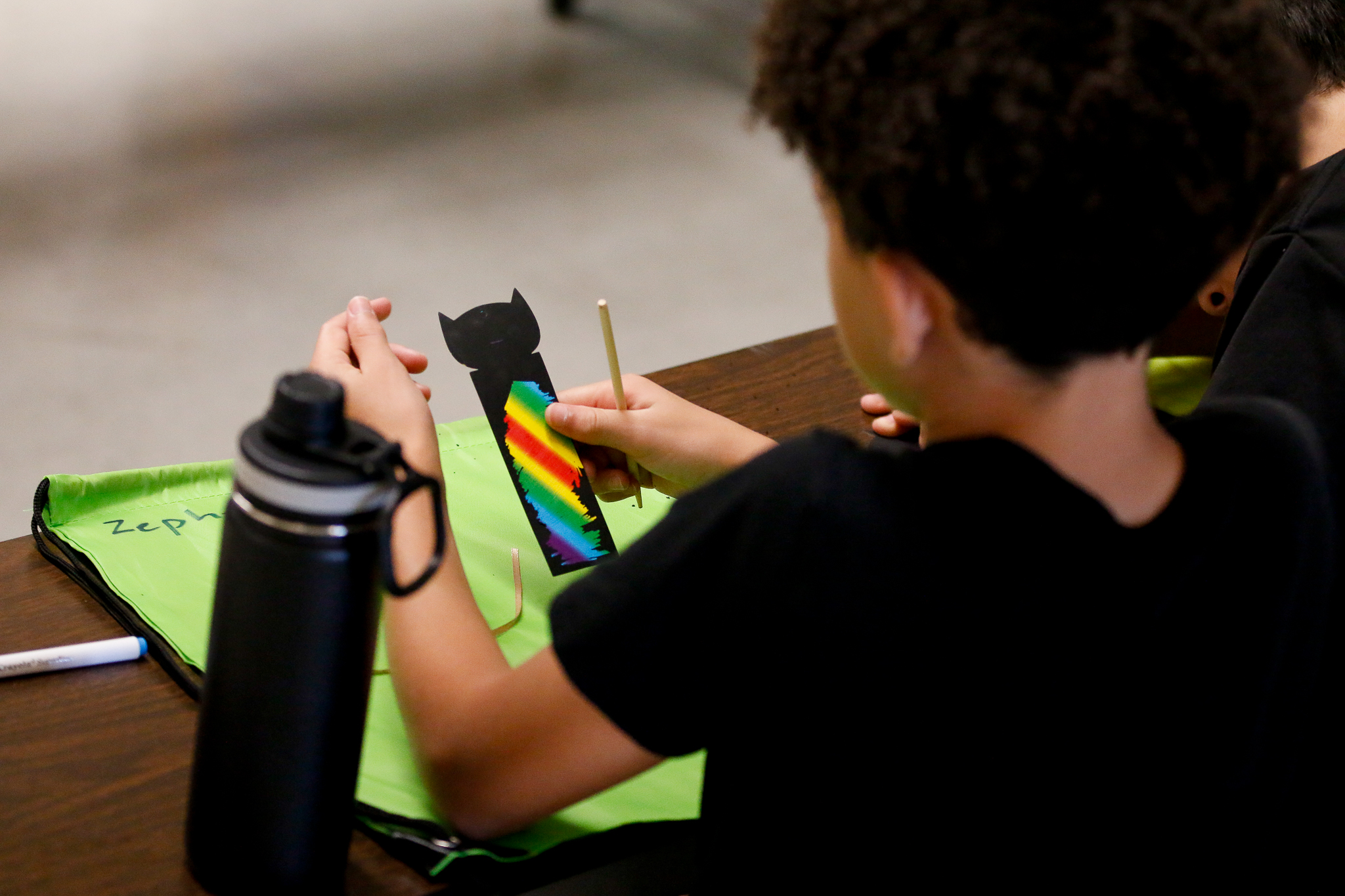 A boy looks at a colorful bookmark he made