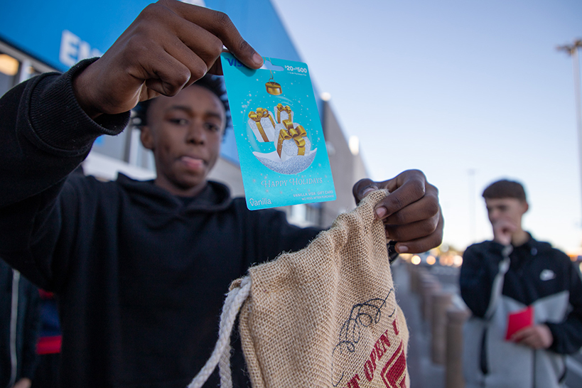 A teen boy holds up a gift card before putting it in a small gift bag