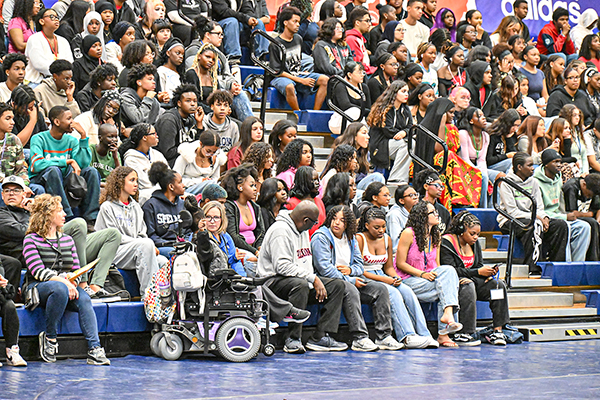 Students sit in the bleachers listening to a presentation