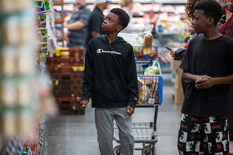 Two boys walk down a grocery store aisle