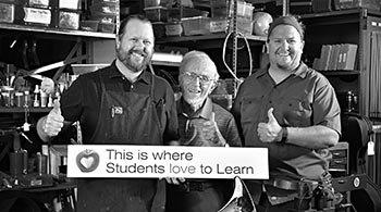 TUSD arts volunteer Dr. Ned Bloomfield poses with Instrument Repair Shop staff.