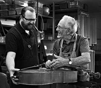 Arts volunteer Dr. Ned Bloomfield and a TUSD Instrument Repair Shop staffer perform repairs on a viola.