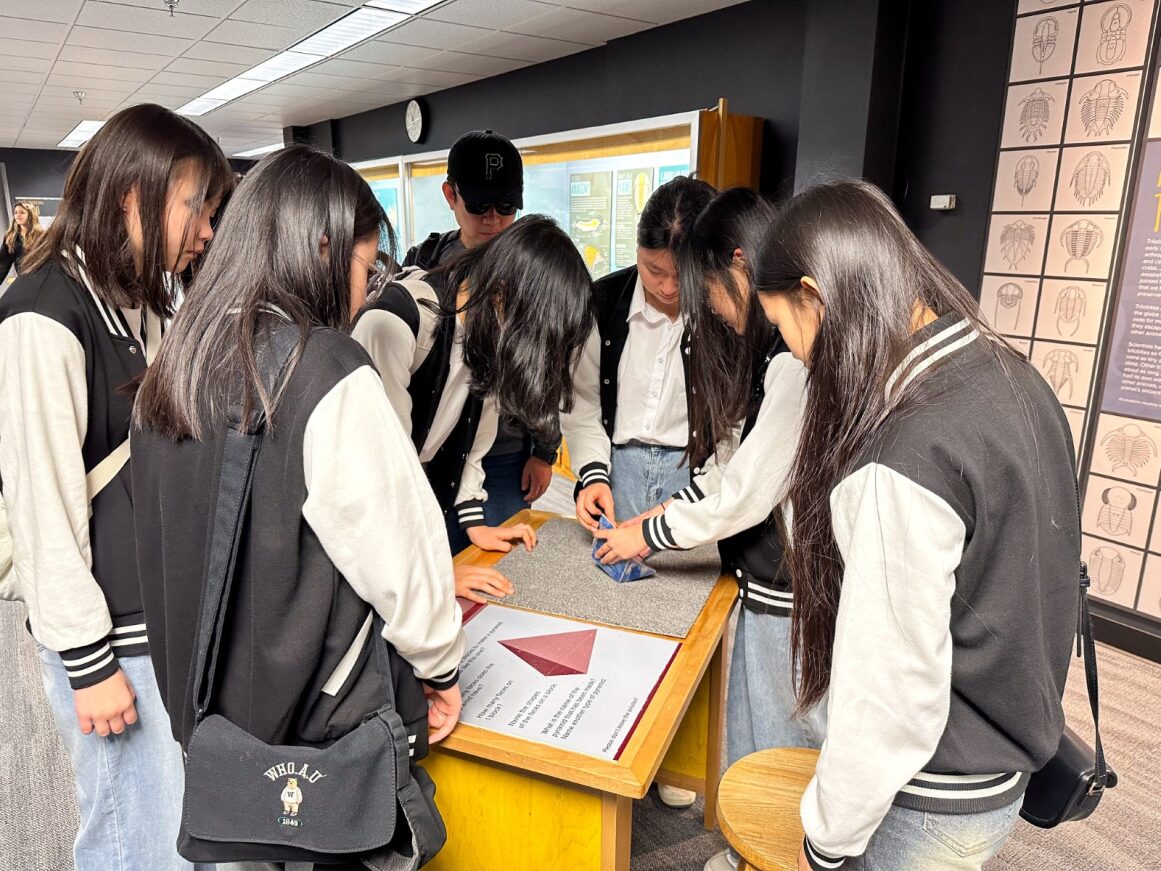 Korean students are gathered around a science exhibit