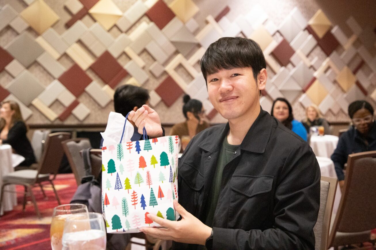 A smiling man holds up his gift bag