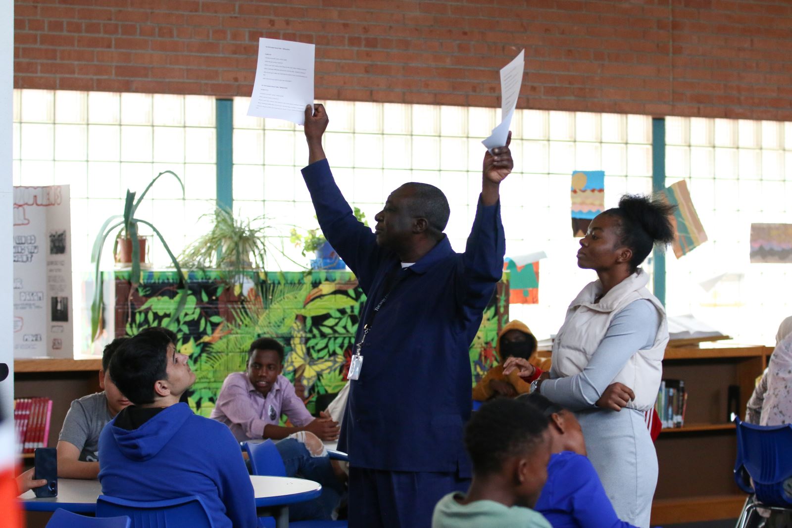 A TUSD staff member holds up pieces of paper for students to see.