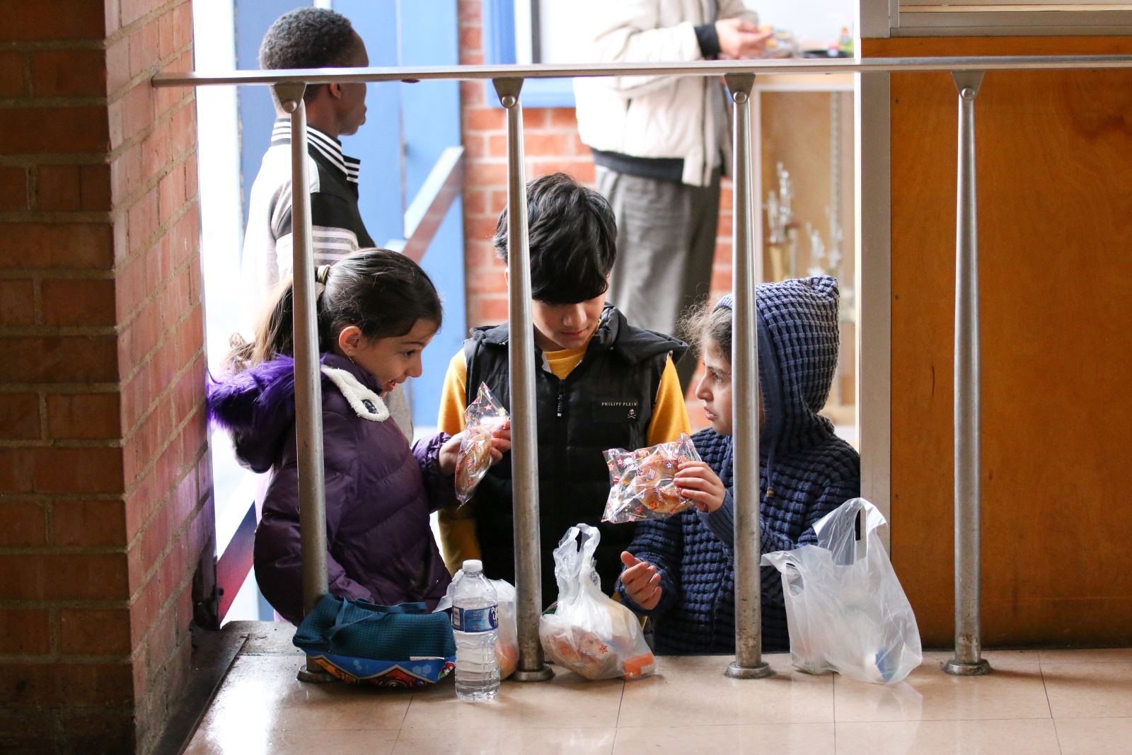 Refugee students enjoy their snacks in the hallway