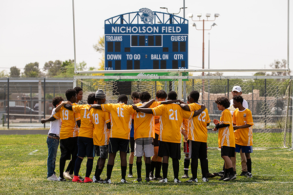 The soccer team wearing yellow jerseys goes in for a team huddle