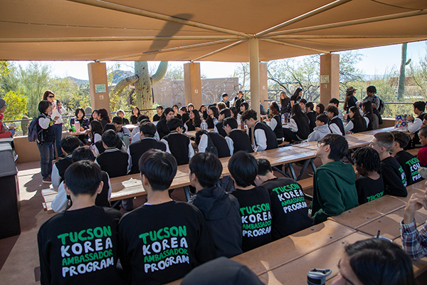 Students wearing their TKAP shirts listen to a talk under the gazebo