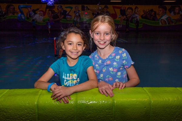 Two girls smile as they take a break from rollerskating