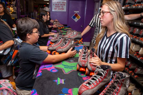 A boy talks to a woman behind a counter to get a pair of rollerskates