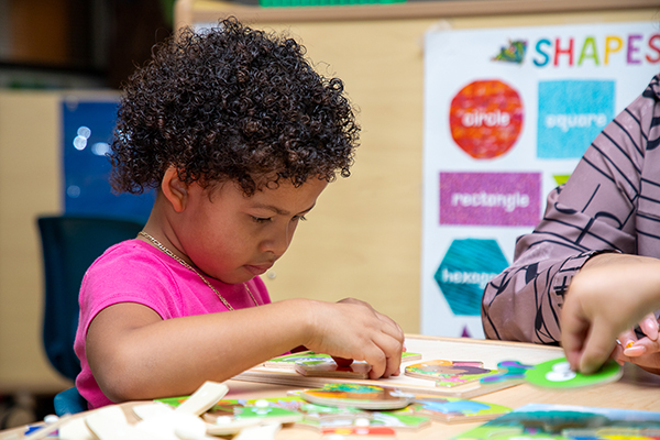 A little girl works on a puzzle