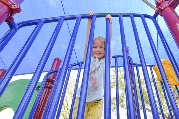 A little girl smiles on the playground equipment