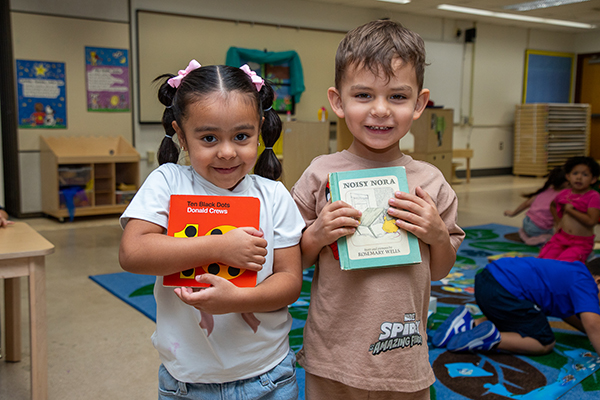 A little girl and little boy proudly hold a picture book