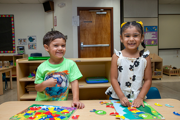 A little boy and little girl smile and play with a puzzle
