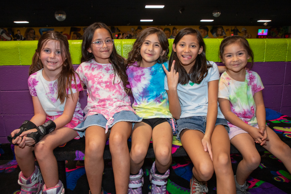 Five girls in tie-dye shirts smile together